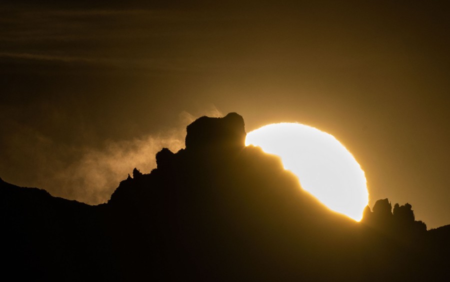 A view of the sunset, sen over craggy mountaintops.