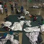 Children lie on green mattresses on the floor and use silver space blankets.