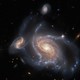 Three spiral galaxies of varying sizes appear close together in the night sky.
