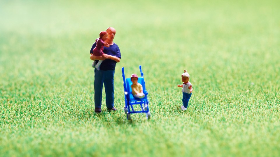 A tiny plastic man stands with his three tiny plastic children