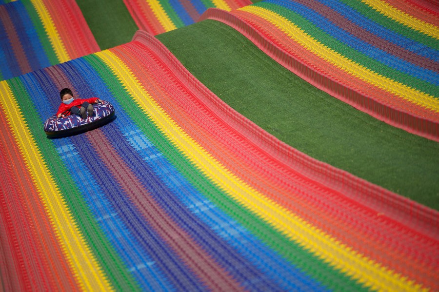 A boy rides down a colorful slide.