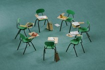 A small circle of green chairs with attached desks and writing tools