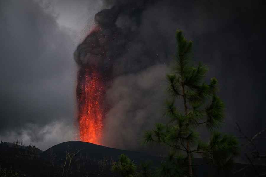 Lava erupts into an ash-darkened sky.