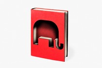 An illustration shows a red hardcover book. The book has been cut into, leaving the shape of an elephant.