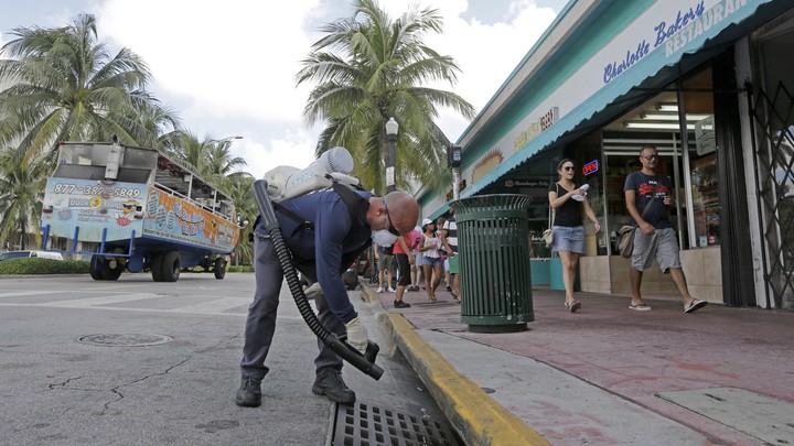 A mosquito control inspector sprays a chemical mist into a storm drain in Miami Beach, Florida, on August 23, 2016.