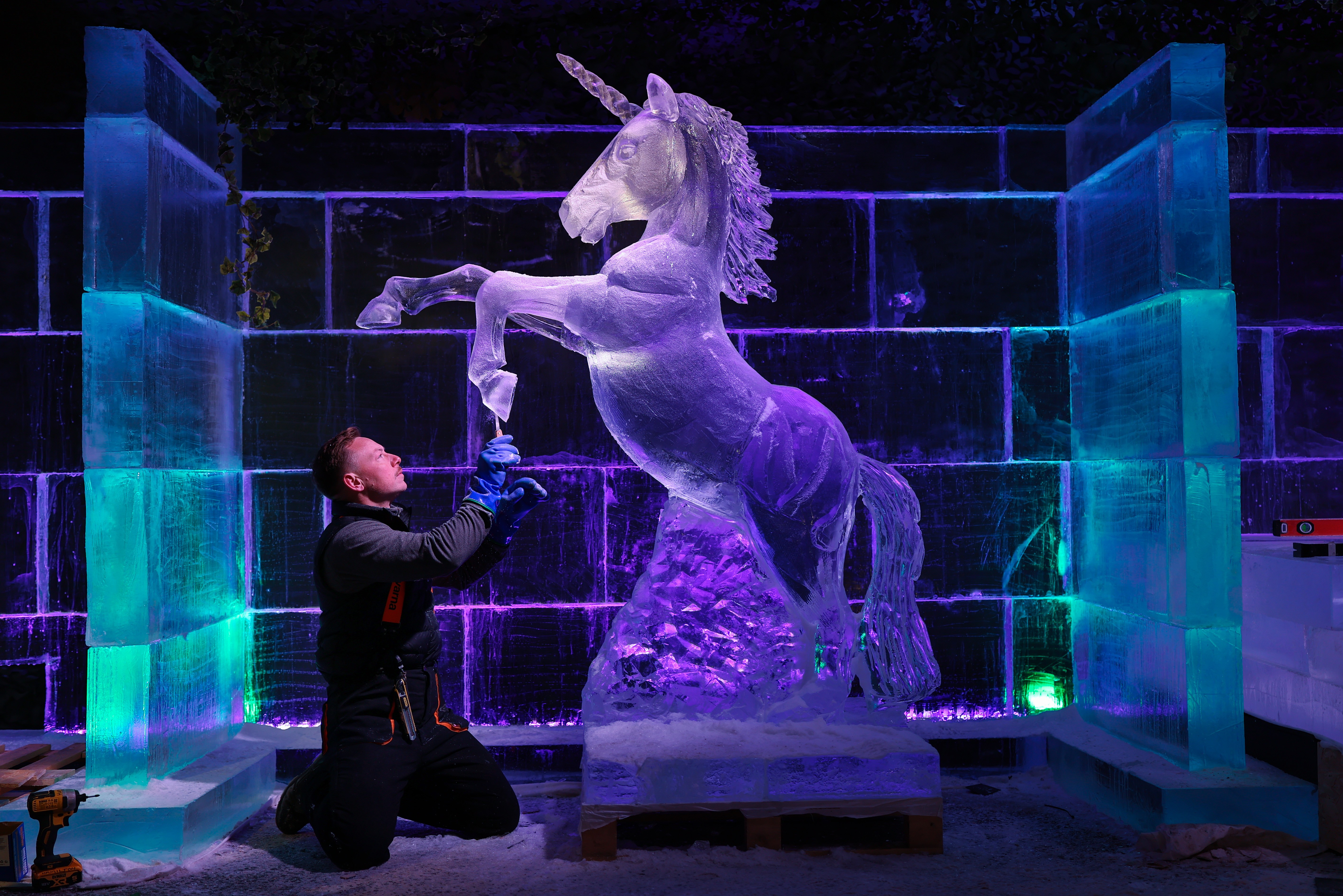 A person works on an ice sculpture of a unicorn.