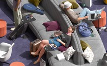 detail from illustration of travelers relaxing on large gray sofa in purple-carpeted lounge