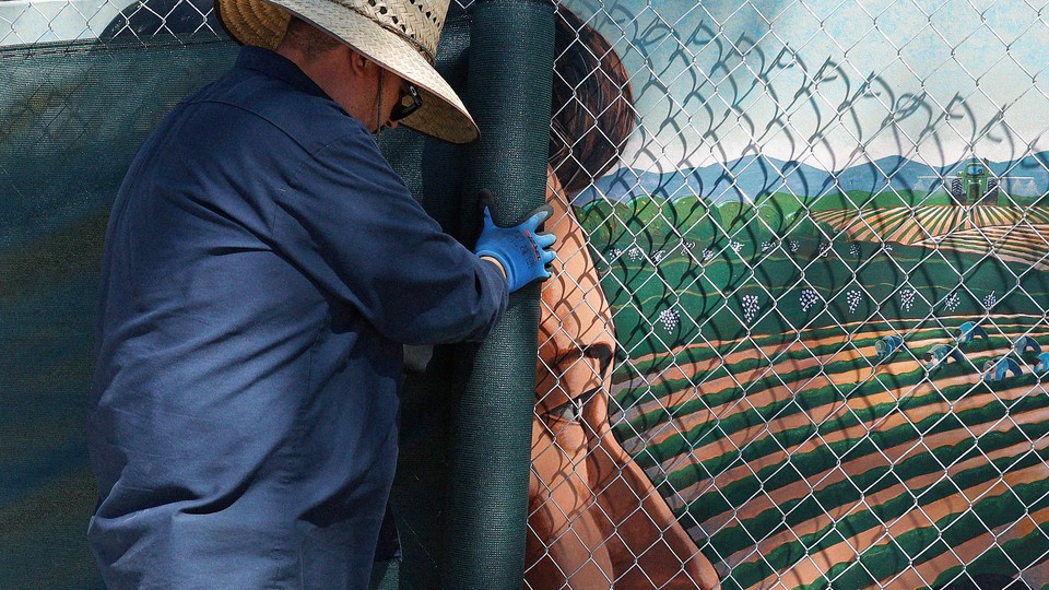 A man covers up a mural of Cesar Chavez