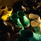 A photograph of eight pairs of yellow, green, and black crocs in an entryway.