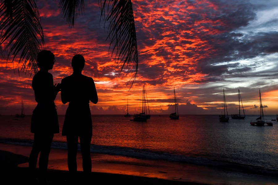 People watch the sunset on the beach on a Caribbean island.