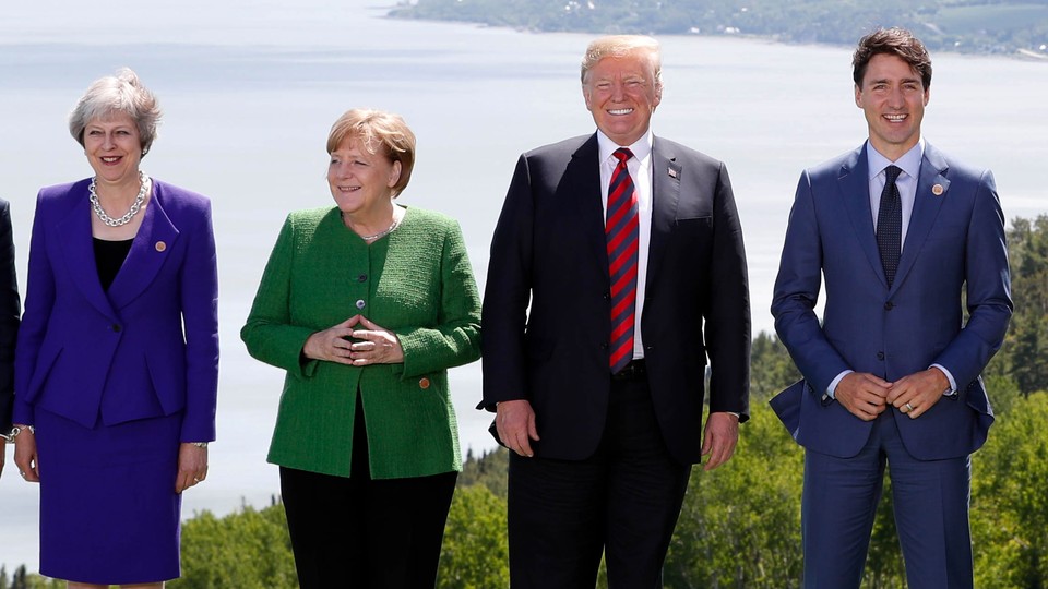 Theresa May, Angela Merkel, Donald Trump, and Justin Trudeau pose during a family photo at the G7 summit in the Charlevoix city of La Malbaie