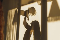A photograph of shadows on wall of mom playing with her daughter, framed by windows