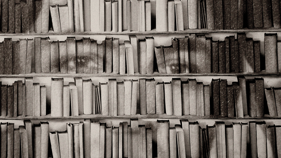 black and white photo of a man looking out from a bookshelf