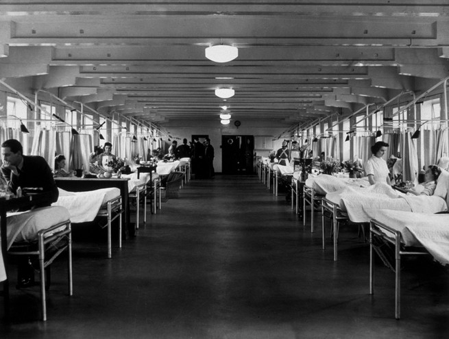 Rows of hospital beds with windows open behind them