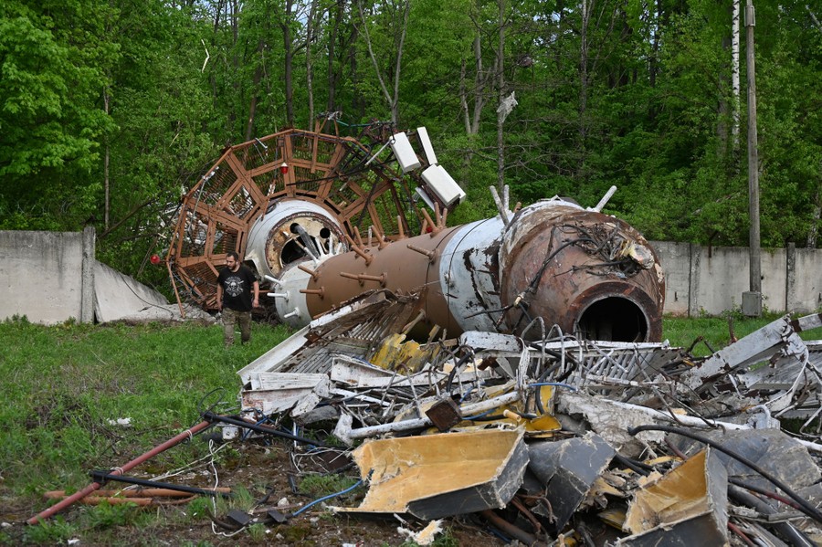 A person walks beside the wreckage of a large toppled broadcast tower.
