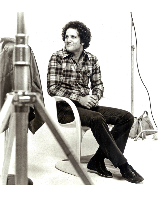 black-and-white photo of Albert Brooks with film equipment on set