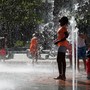A girl plays near a water fountain on a summer day. 