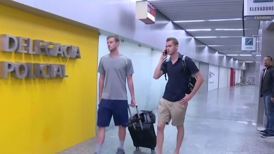 U.S. Olympic swimmers Gunnar Bentz and Jack Conger walk Wednesday to the airport police station office at Rio's international airport.