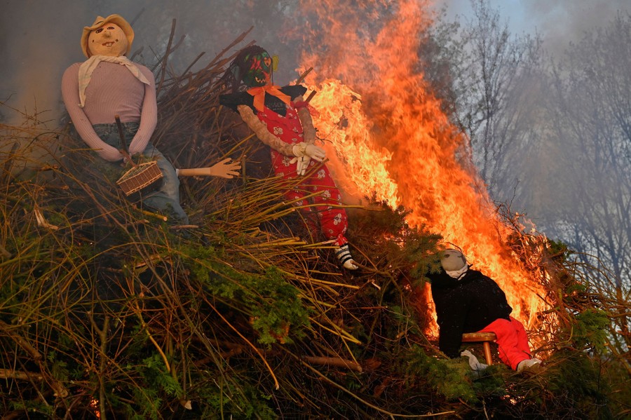 Several stuffed dolls are burned atop a pile of brush.