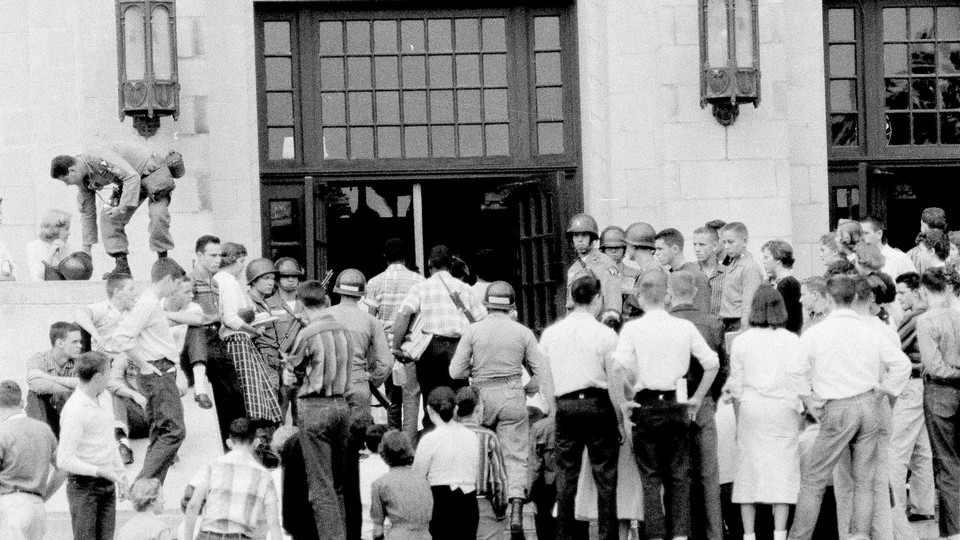 Black students are escorted through the front door of Central High School in Little Rock, Ark., Sept. 26, 1957. 