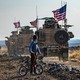 A Syrian boy on a bicycle watched a convoy of US armored vehicles drive away on a dirt road in northeastern Syria.
