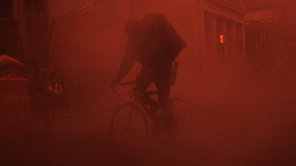 A person riding a bicycle in a red fog 