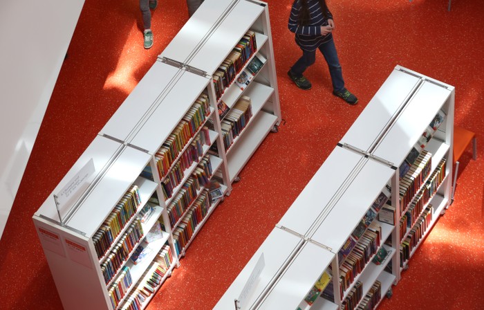 People walk between library shelves