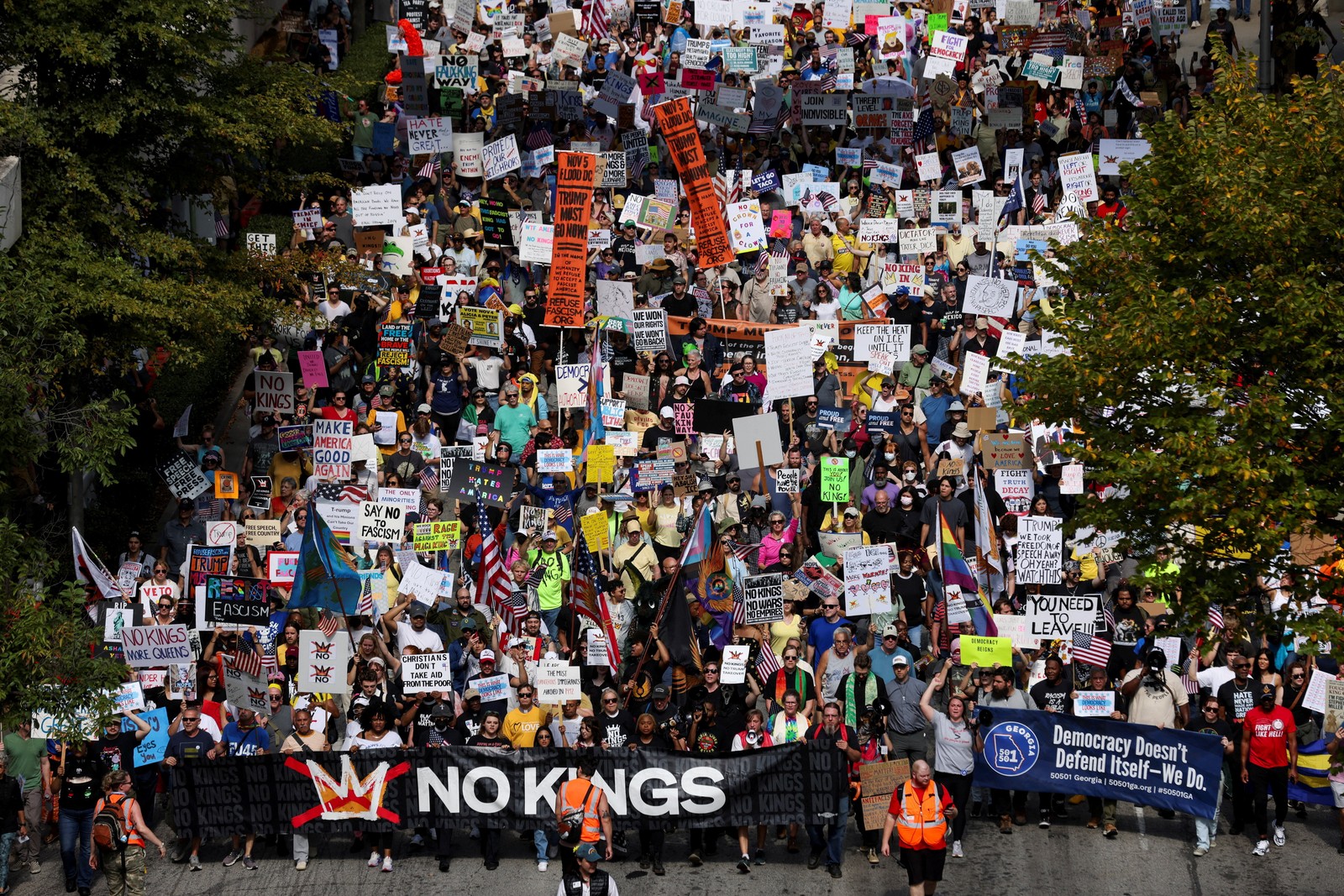 A crowd of protesters marches downa street, carrying signs.