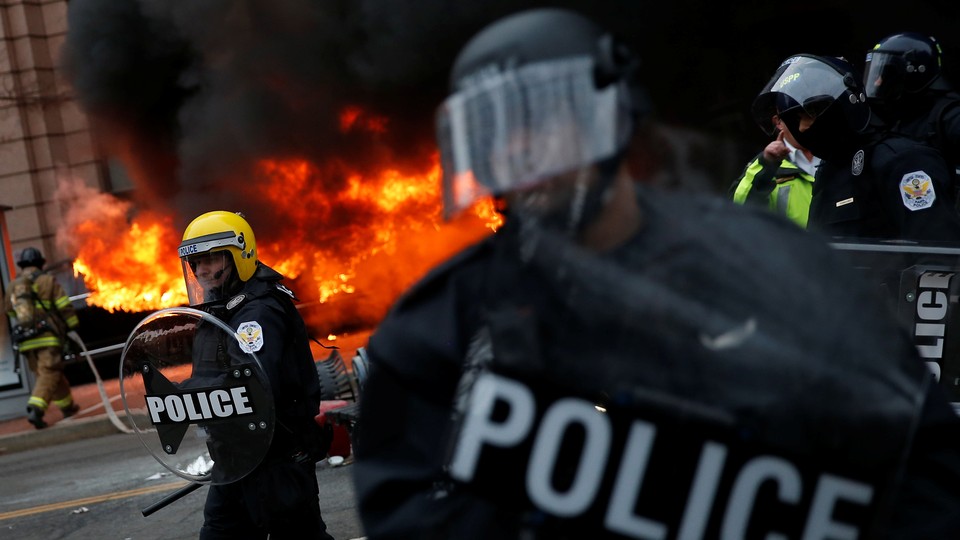 Firefighters arrive as police stand guard in front of a limousine which was set ablaze during a protest against President Donald Trump on January 20, 2017, in Washington, D.C.