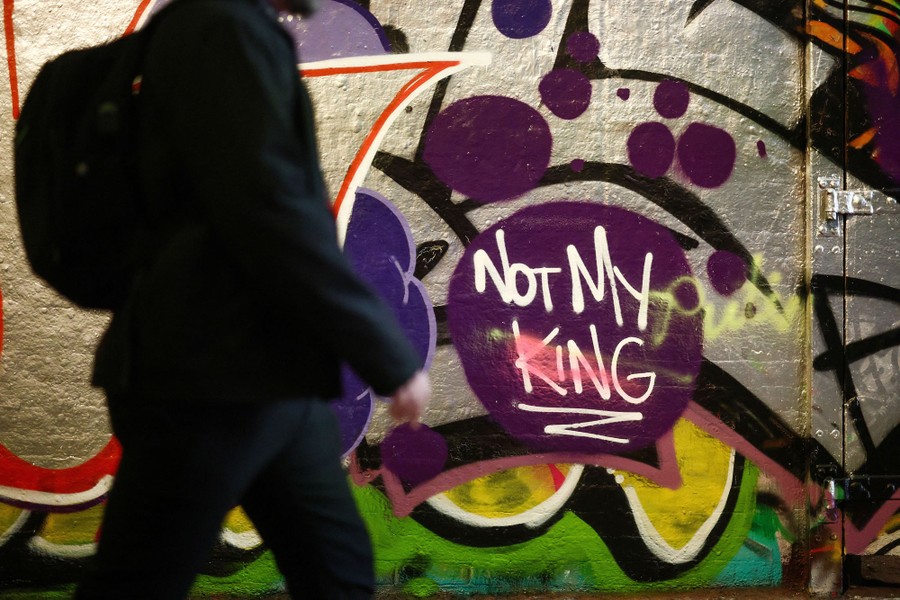 A person walks past graffiti that reads "Not My King."
