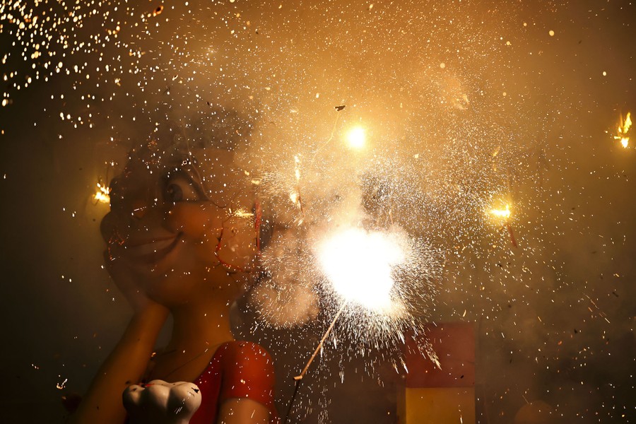 Fireworks explode beside the head of a large human figurine.