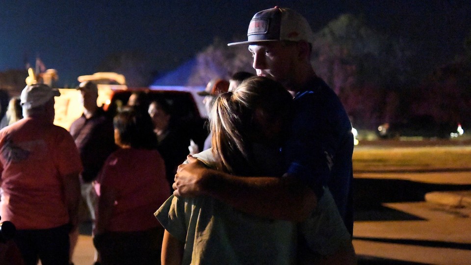 Two people embrace at a nighttime vigil.