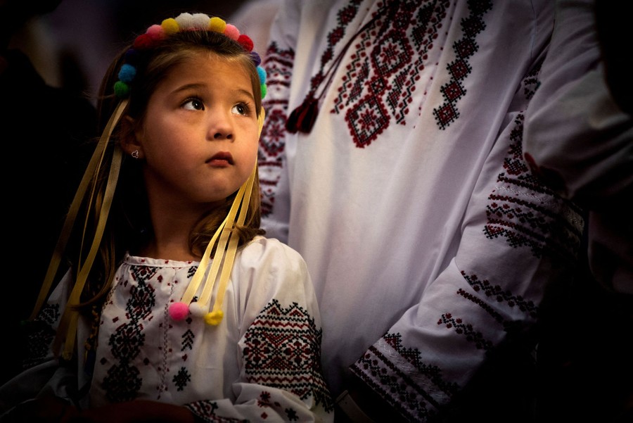 A young girl in traditional Ukrainian clothing stands next to several adults.
