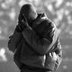 A black-and-white image of Kanye West, with his head bowed and his hands over his face, at a 'Donda' listening event last month