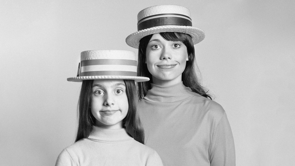 Mother and daughter pose with straw hats.