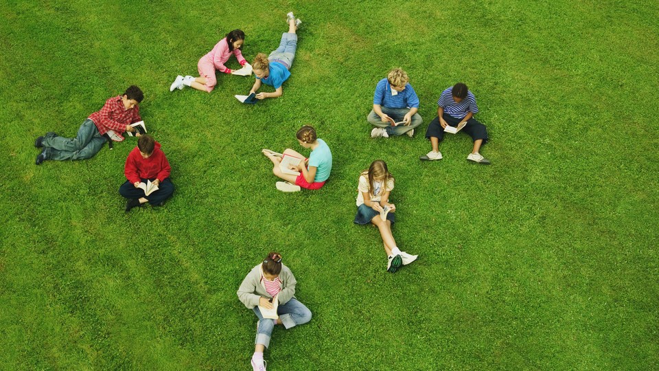 Group of children reading on grass, elevated view