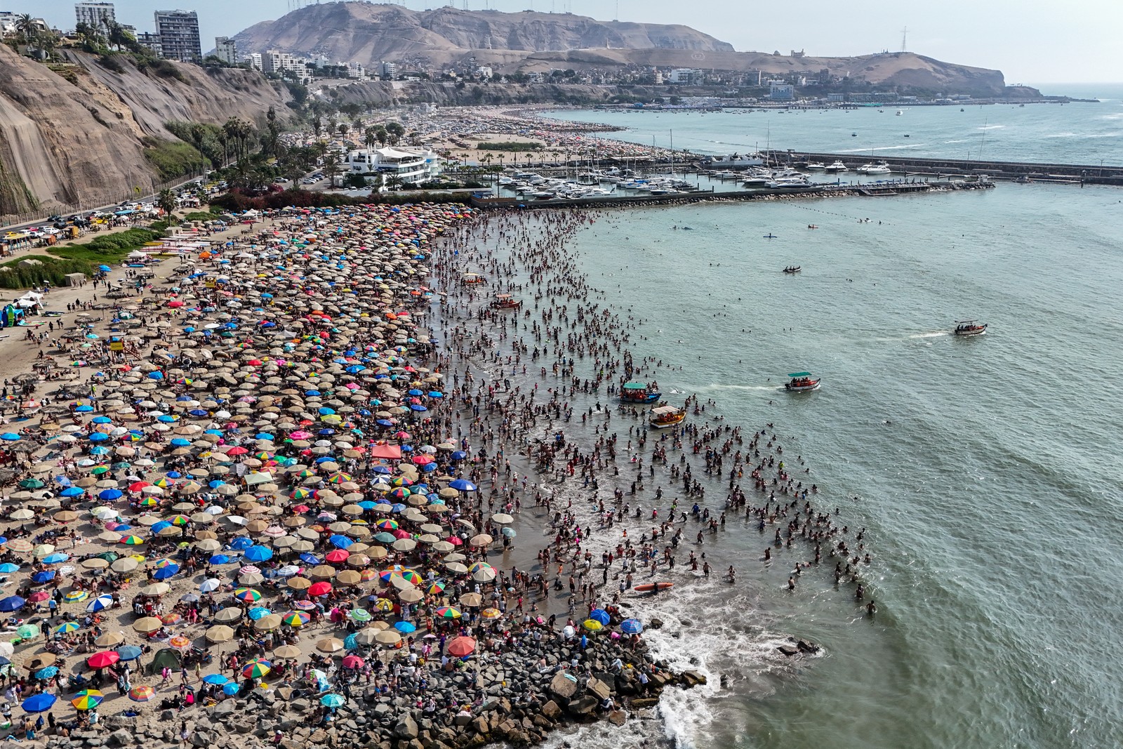An aerial view of a very crowded beach, covered with many umbrellas
