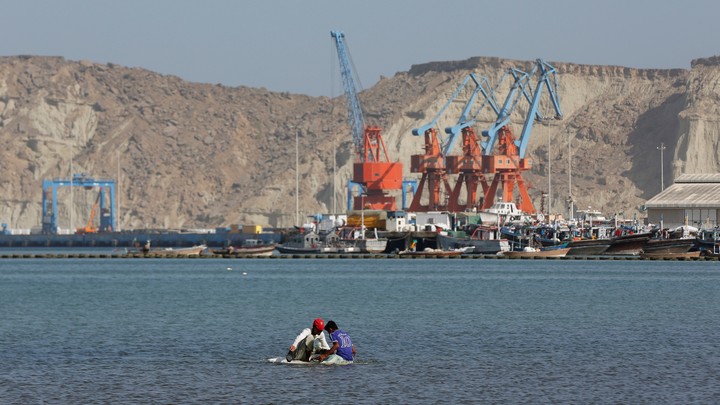 Boys sit on a piece of styrofoam sheet as they search for crabs in front of the Gwadar port in Pakistan.