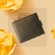 A black and white photo shows a leather wallet with a series of dollar bills coming out of the top