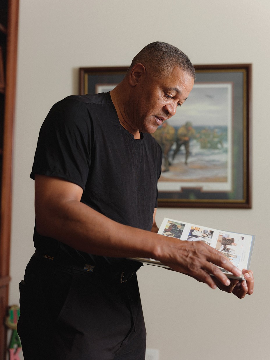 photo of man in dark t-shirt and pants looking through binder-style photo album of printed photos