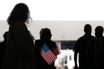 A group of people are silhouetted while holding small American flags