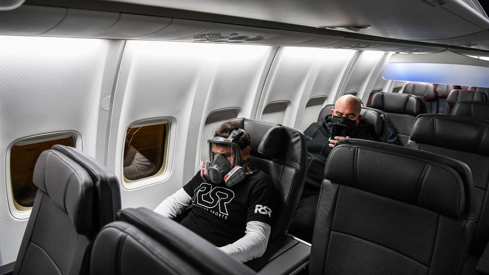 A man wears a gas mask as he travels on a flight from Miami to Atlanta on April 23, 2020.