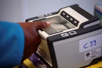 A woman places her thumb on a fingerprint scanner.