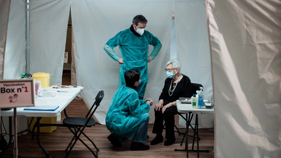 A woman speaks with health providers at a vaccination center in France.
