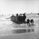 Marines in the process of disembarking from a ship onto a beach.