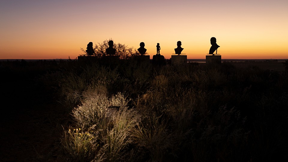 Photo of silhouettes of busts on pedestals during sunset