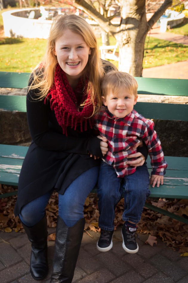 Sarach Schuyler and her son, Asher, sit on a park bench in coordinated red outfits.