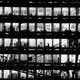 Black-and-white picture of office building, with windows showing silhouettes of people working