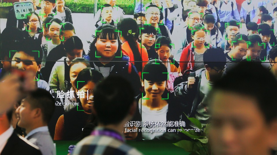 Visitors walk past a screen showing a demonstration of facial-recognition software at the Security China 2018 exhibition on public safety and security in Beijing.