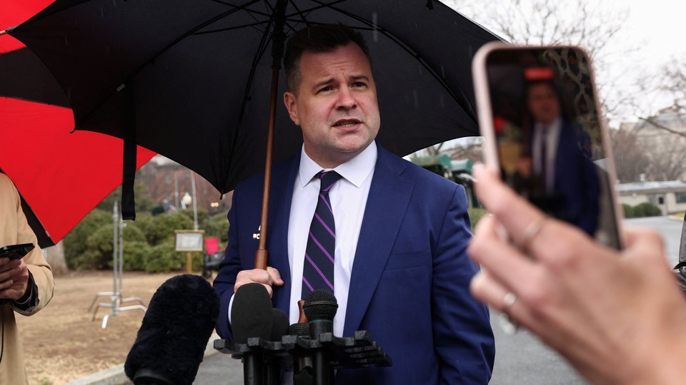 An image of Bill Pulte carrying an umbrella being recorded while speaking to the press